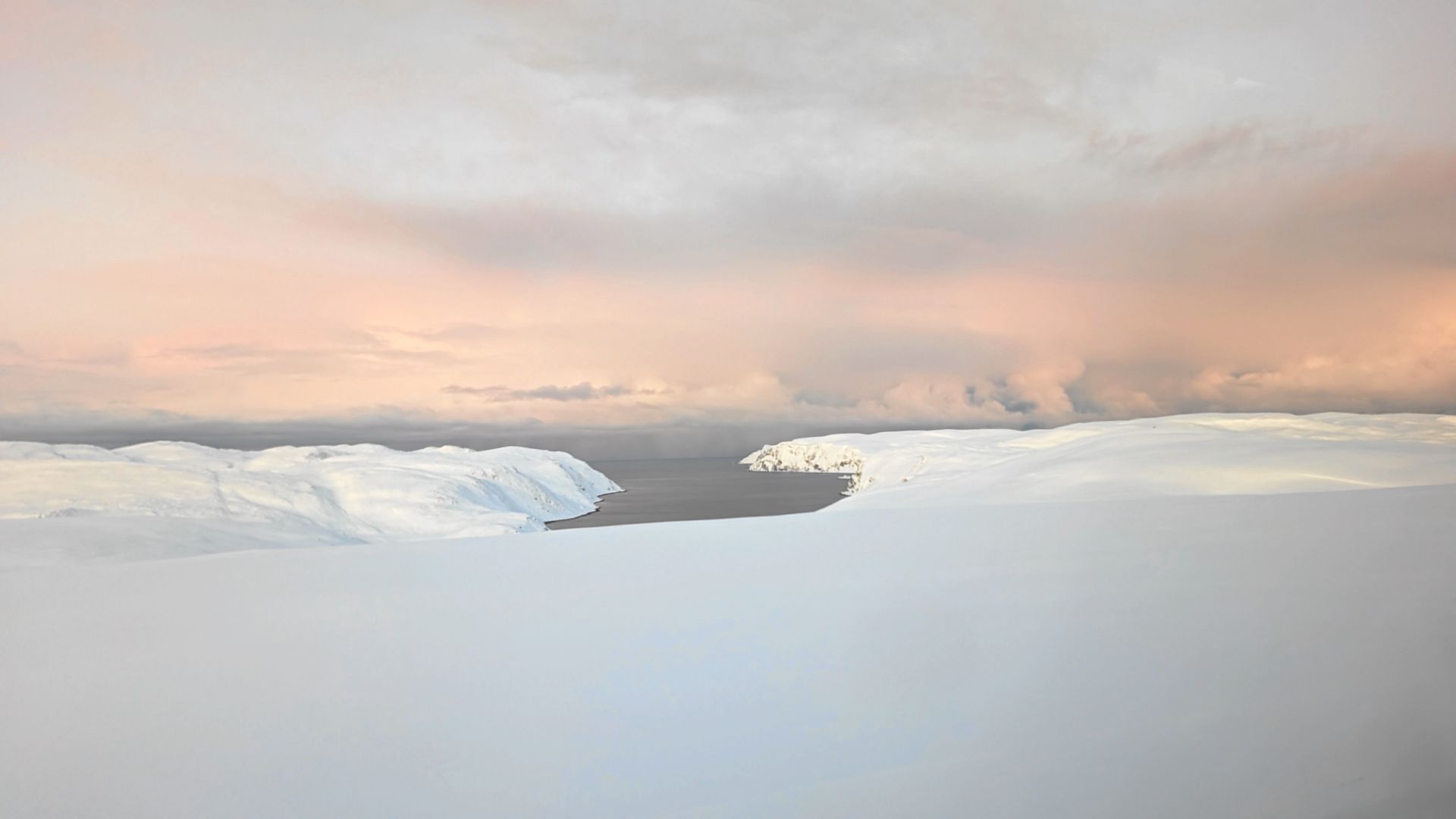 Eisberge unter einem pastellfarbenen Himmel mit tief hängenden Wolken.