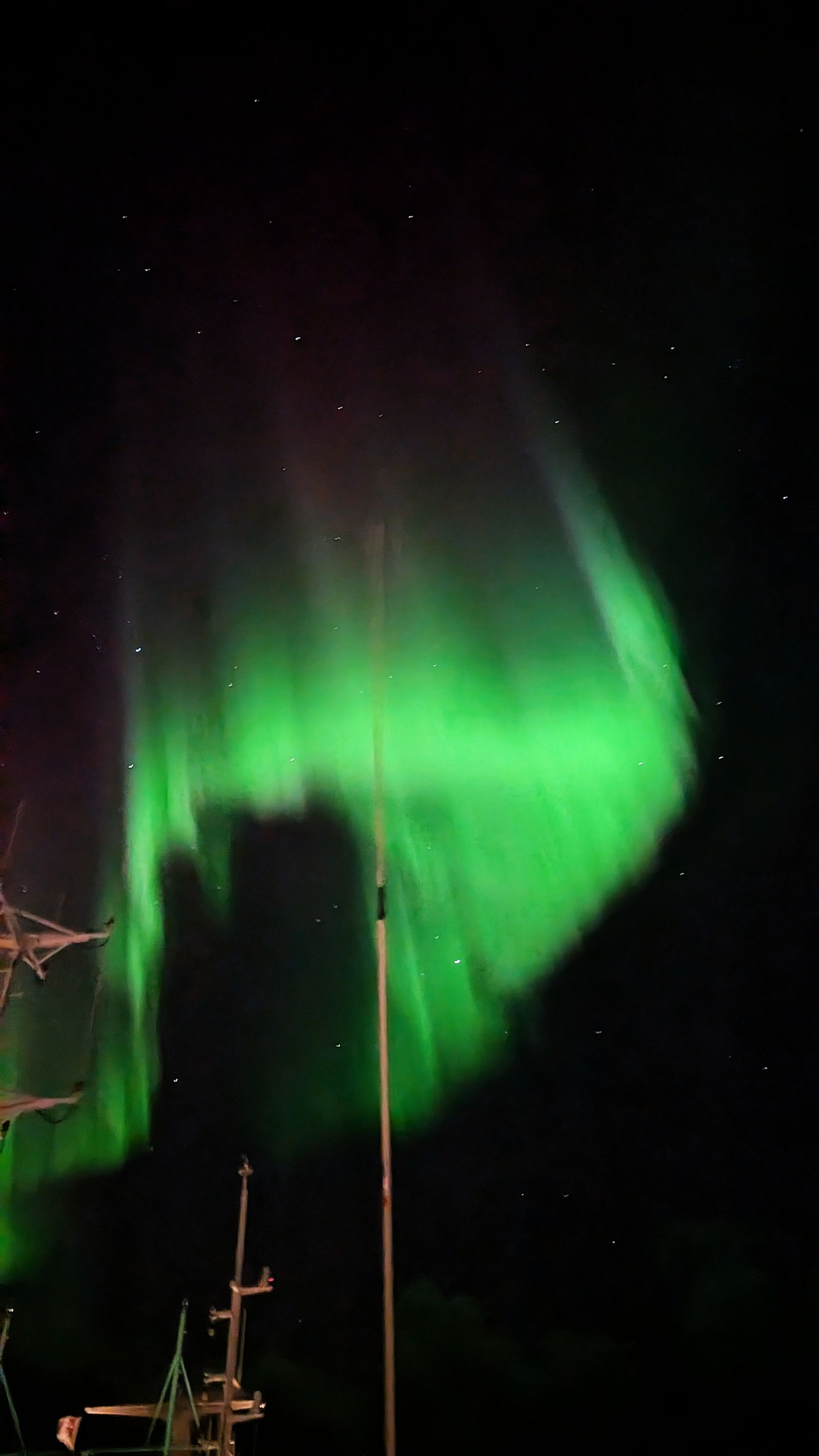 Grüne Aurora borealis über dunklem Nachthimmel, sichtbar mit Andeutungen von Sternen.