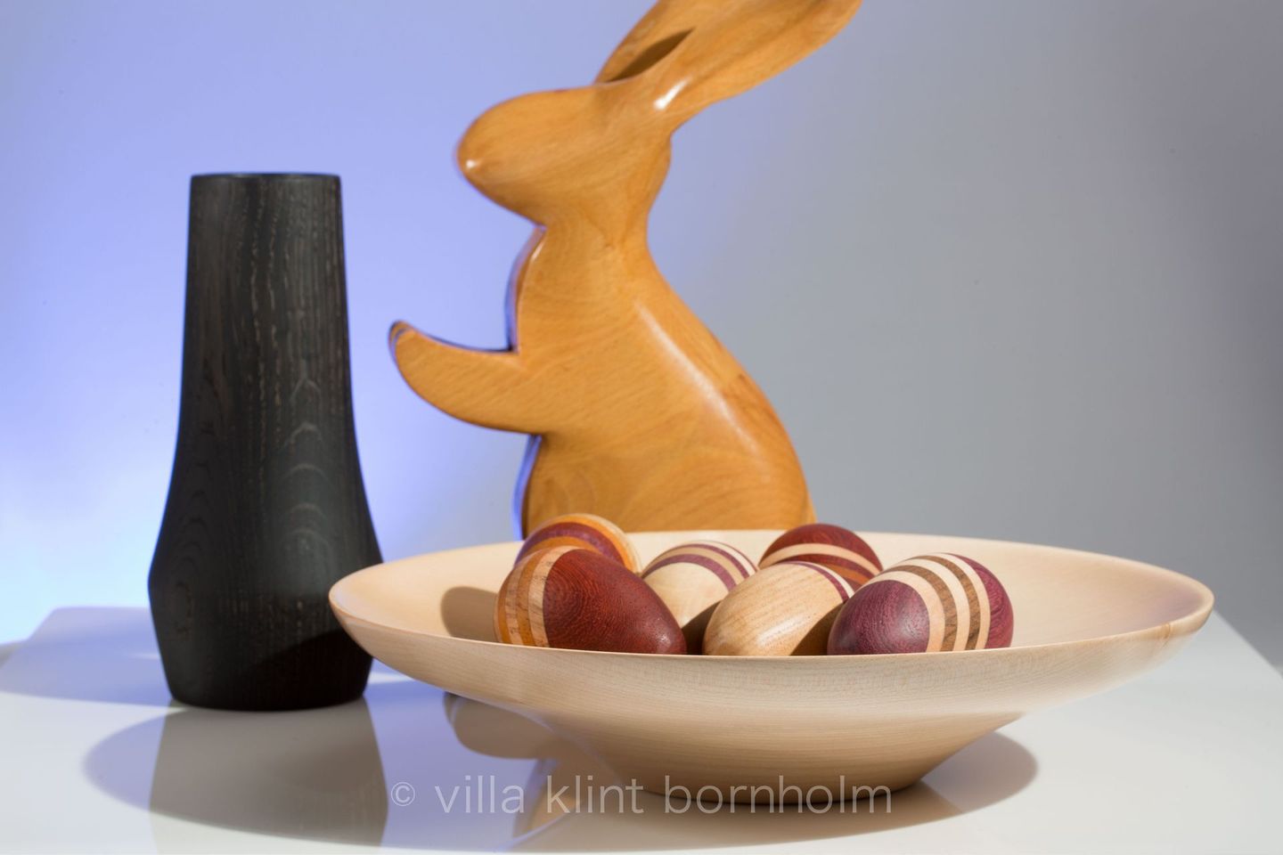 Osterbild: ein Osterhase und mehrfarbig gestreifte Ostereier