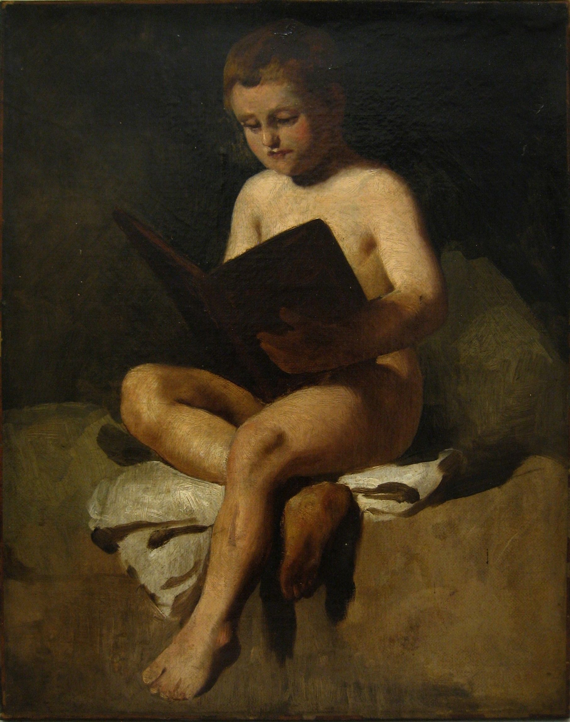 Nacktes Kind sitzt und liest ein großes Buch. Dunkler Hintergrund, sitzend auf einem Tuch und einem Kissen.