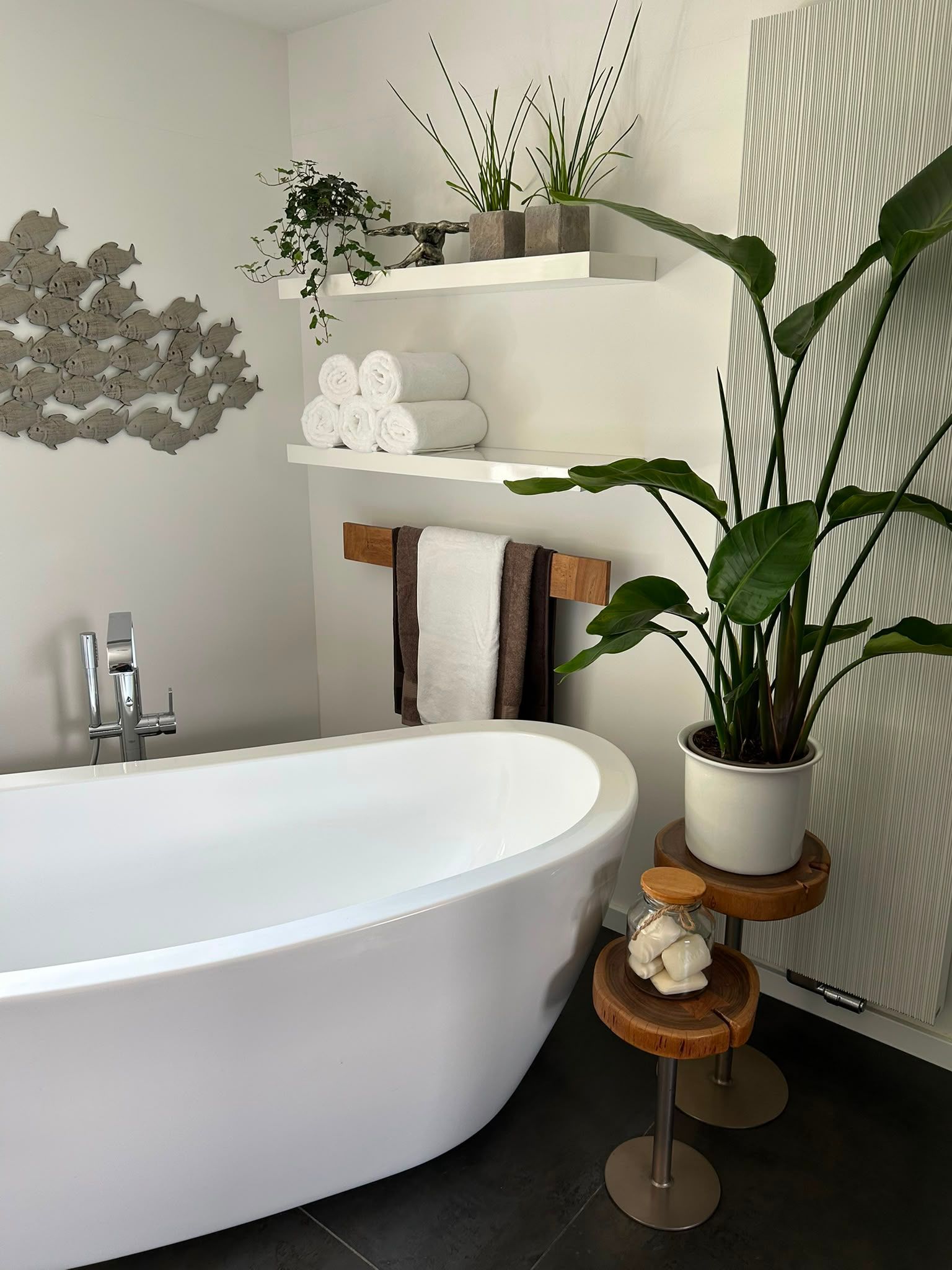 Modernes Badezimmer mit freistehender Badewanne, Wandregalen, Pflanzen und gemusterter Wanddekoration