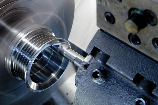 Eine Metalldrehmaschine schneidet Nuten in ein zylindrisches Metallteil, wobei ein scharfer Drehmeißel an der rotierenden Oberfläche anliegt.