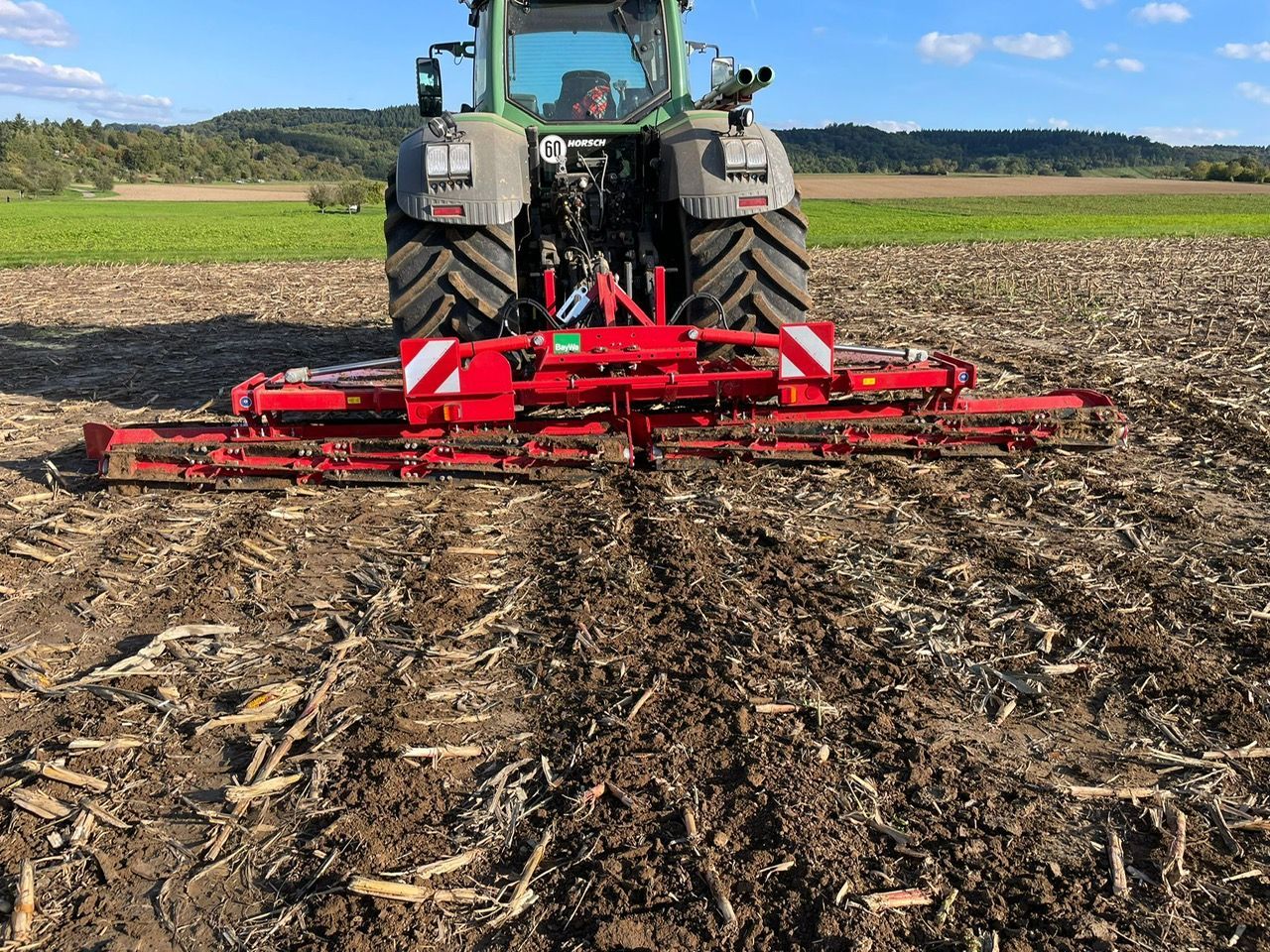 Fendt-Traktor mit angehänter Horsch-Walze nach dem bearbeiten der Rapsstoppel auf dem Feld, unter blauem Himmel.