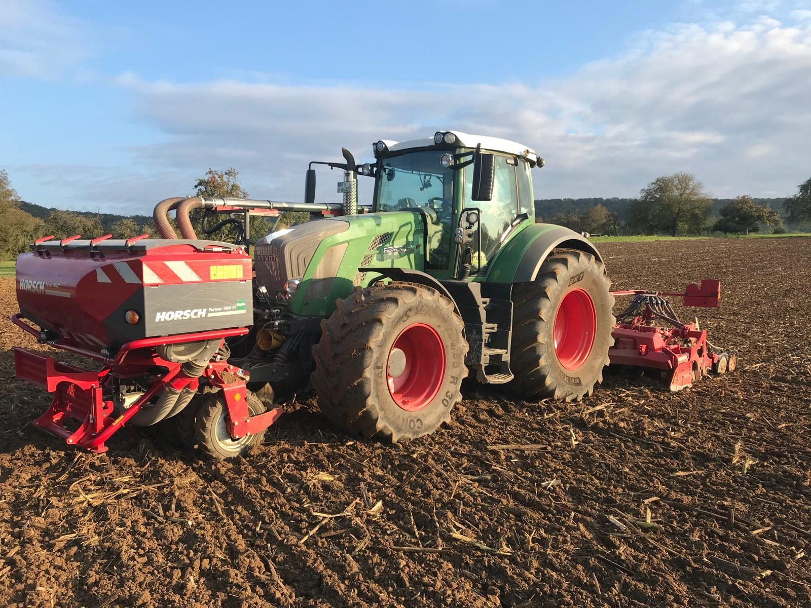 Fendt-Traktor mit angebauter Horsch-Drillmaschine beim Arbeiten an einem sonnigen Tag.