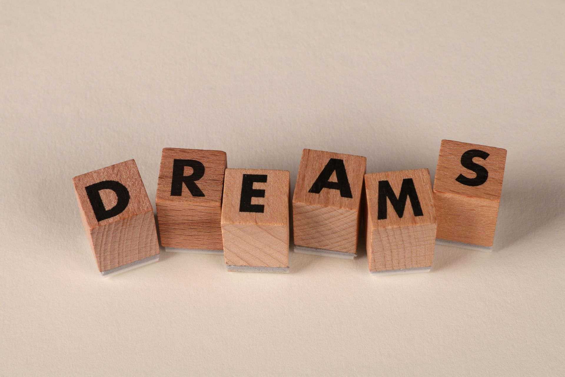 Holzwürfel mit dem Wort „DREAMS“ auf beigem Hintergrund