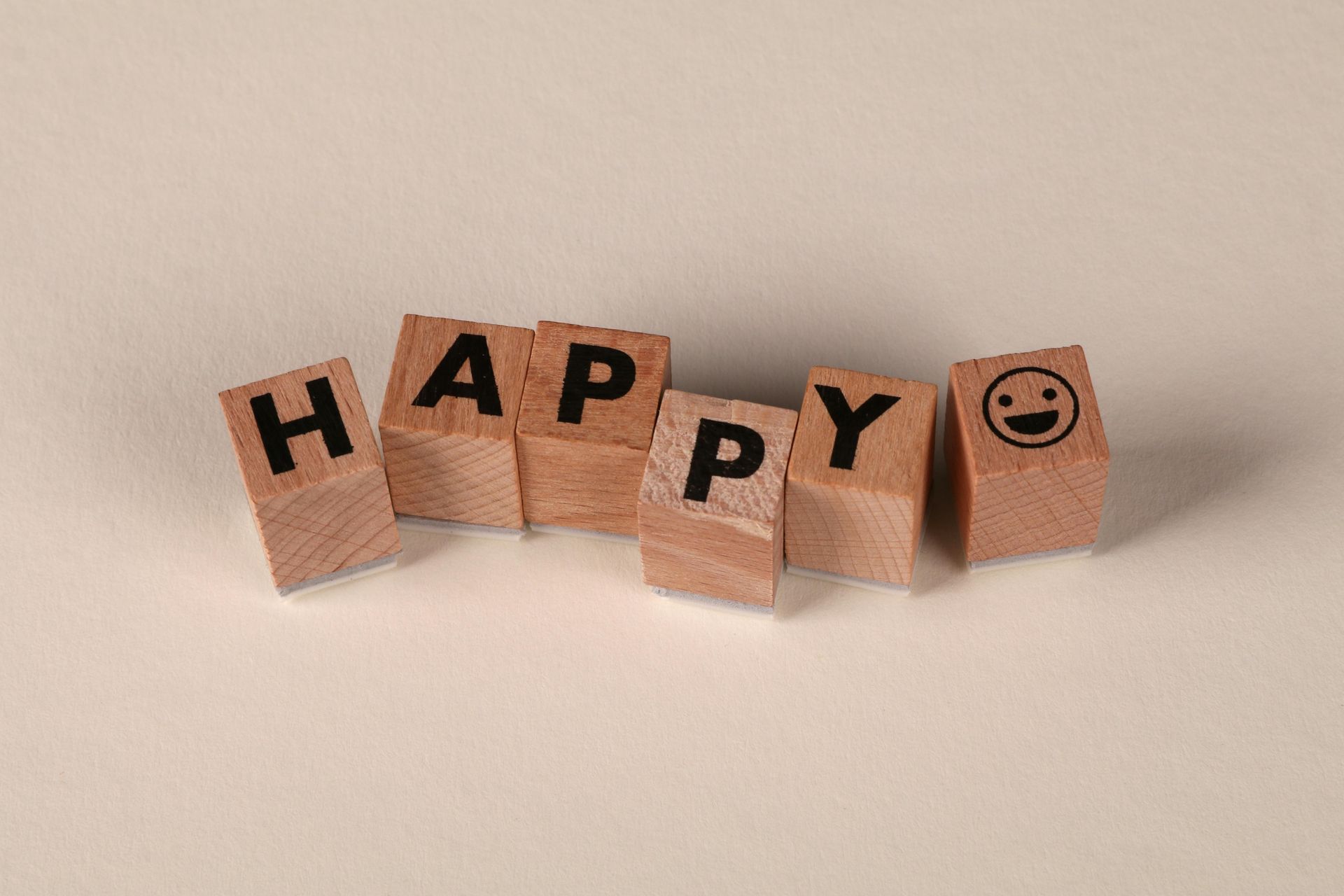 Holzwürfel mit dem Wort „HAPPY“ und Smiley am Ende.