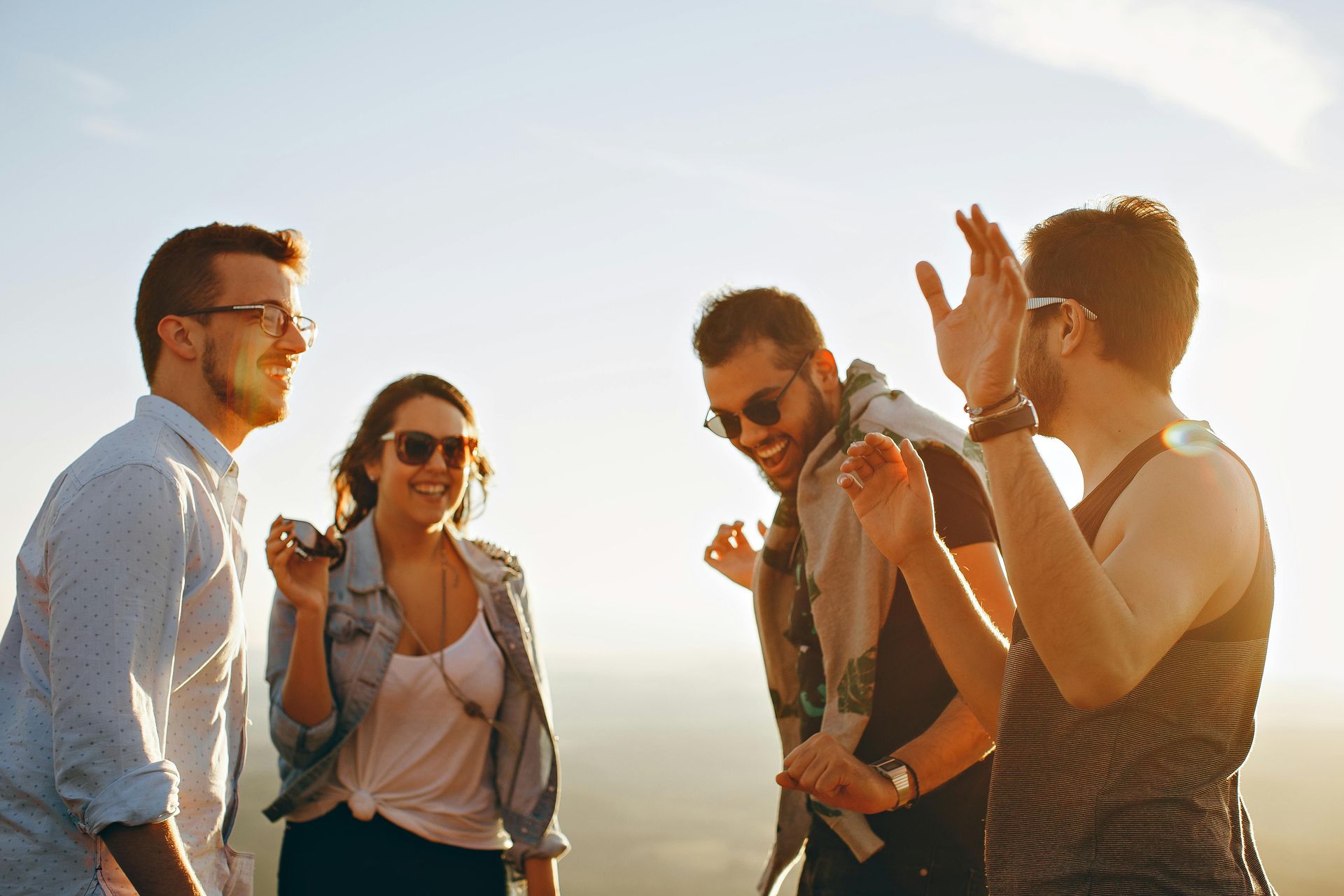 Vier junge Erwachsene lachen gemeinsam im Sonnenlicht