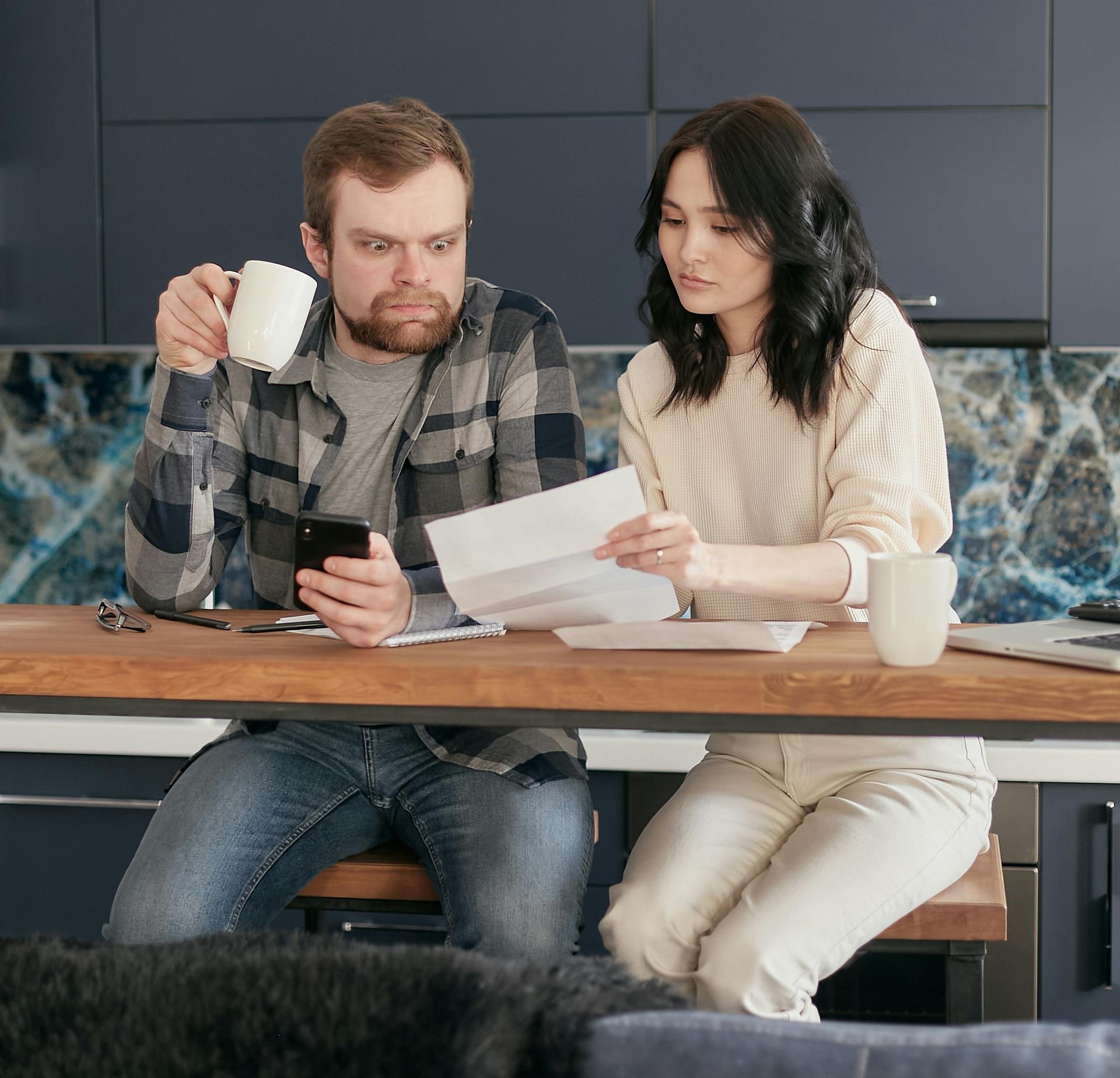 Paar sitzt am Tisch und schaut gemeinsam auf Rechnungen