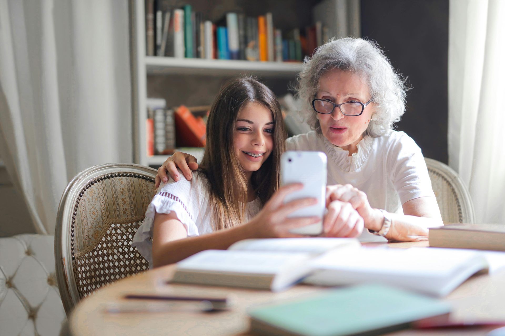 Ältere Frau und junges Mädchen schauen gemeinsam aufs Smartphone