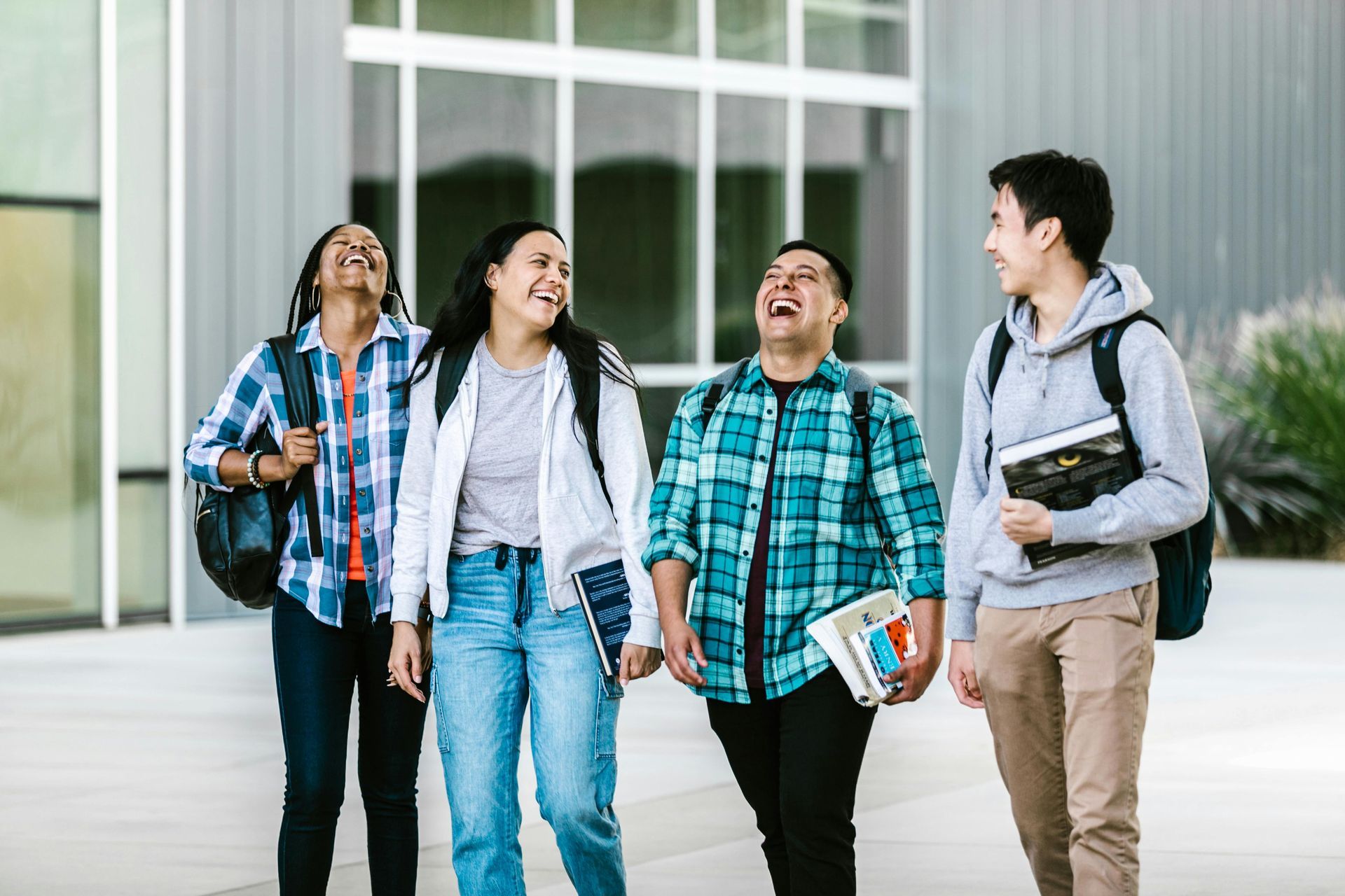 Vier junge Erwachsene lachen gemeinsam auf dem Campus