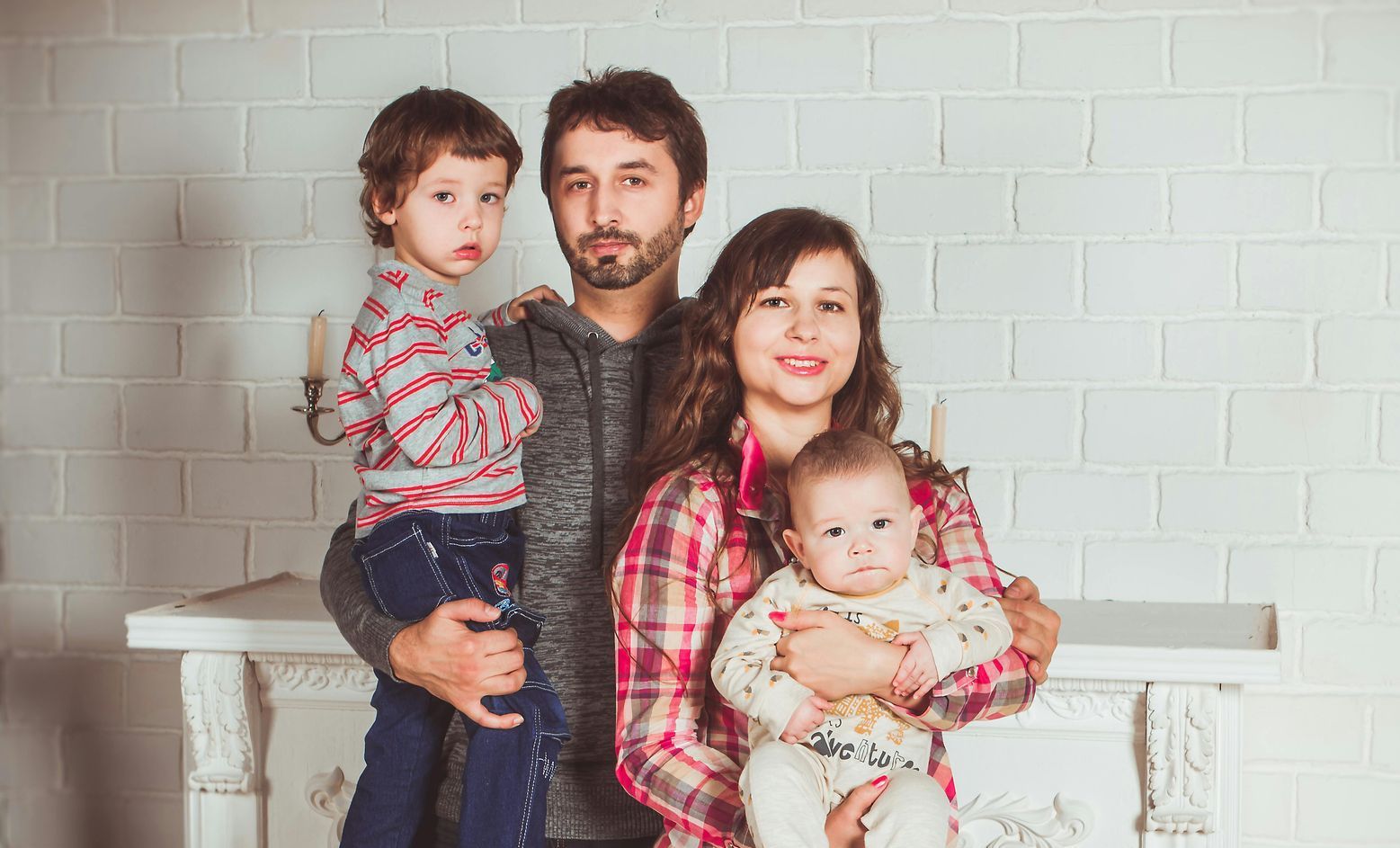 Junge Familie mit zwei Kindern vor weißer Wand