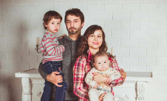 Junge Familie mit zwei Kindern vor weißer Wand