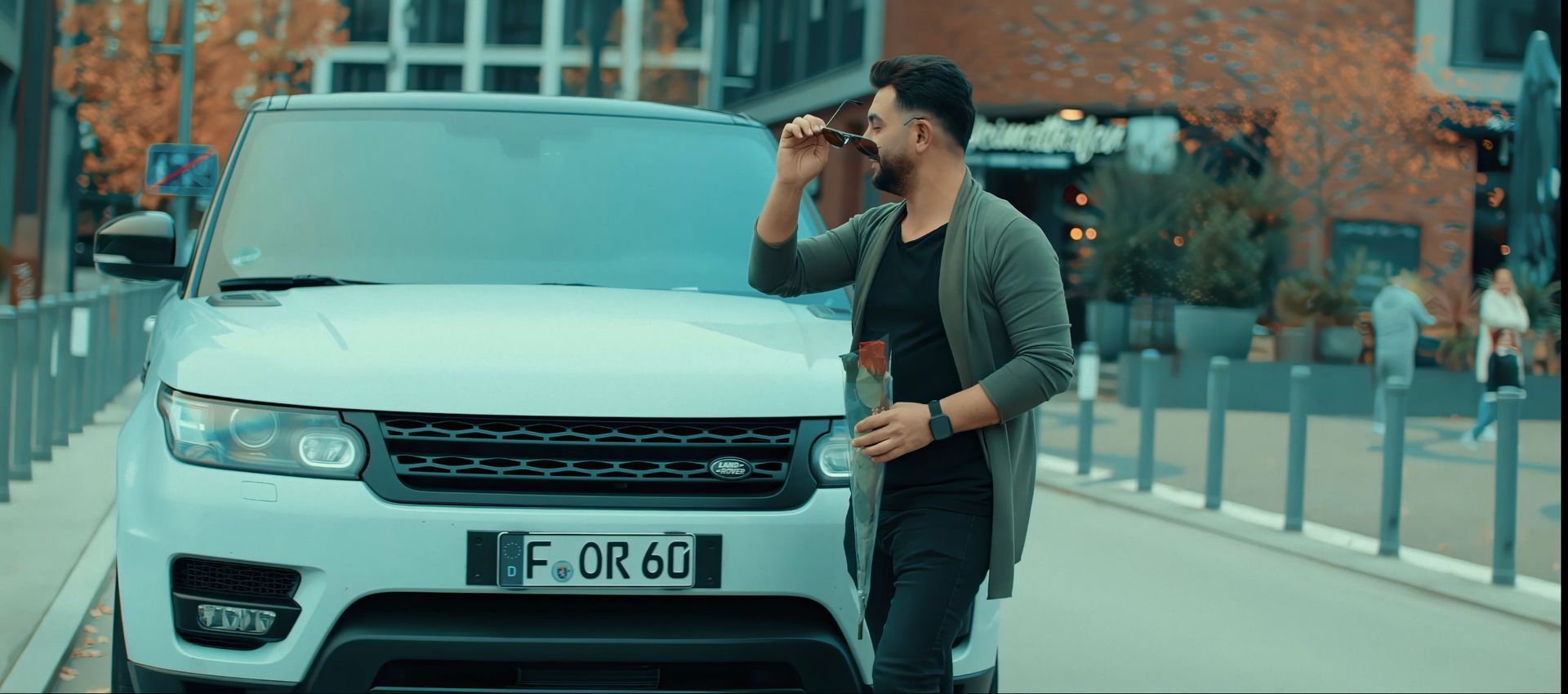 Grup 12’nin klip çekimi sırasında bir üye, şık bir araba önünde dinamik bir poz veriyor.