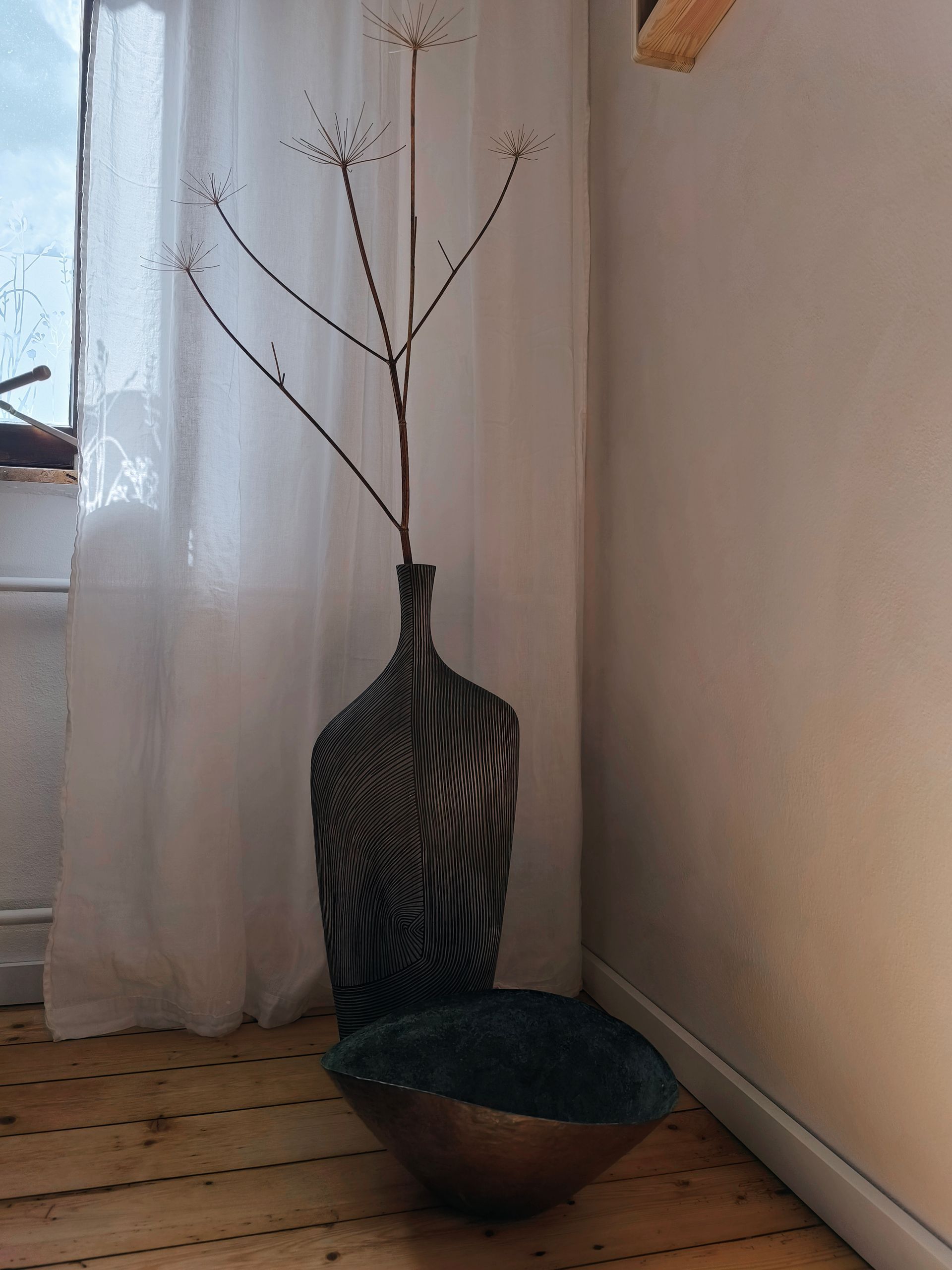 Große Bodenvasen, als Deko im Seminarraum. Darin steht ein Zweig.