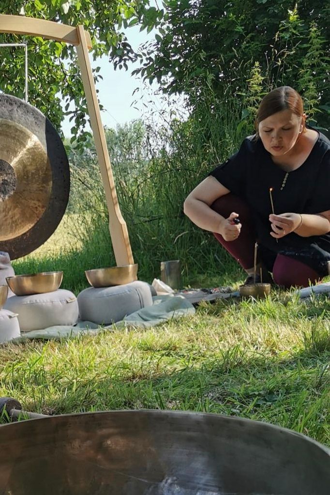 Julia Pantou zündet draußen ein Räucherstäbchen an, auf einer Obstwiese an. Klangveranstaltung unter freiem Himmel, mit Gongl