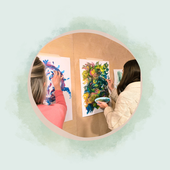 Zwei Frauen malen intuitiv mit bunten Farben auf Papier bei einem Kreativworkshop im Atelier Samenkorn in Detmold.