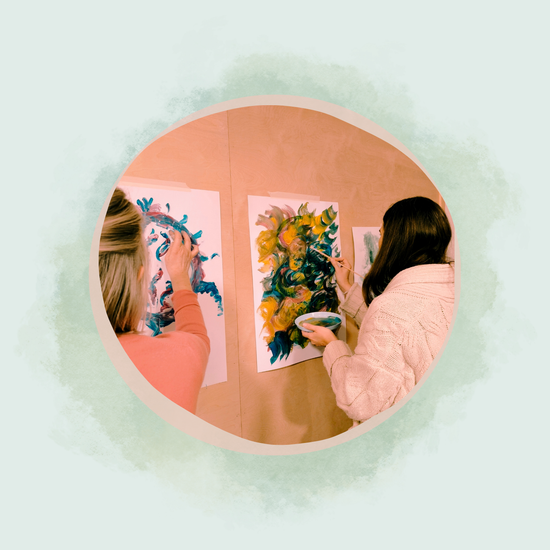 Zwei Frauen malen intuitiv mit bunten Farben auf Papier bei einem Kreativworkshop im Atelier Samenkorn in Detmold.