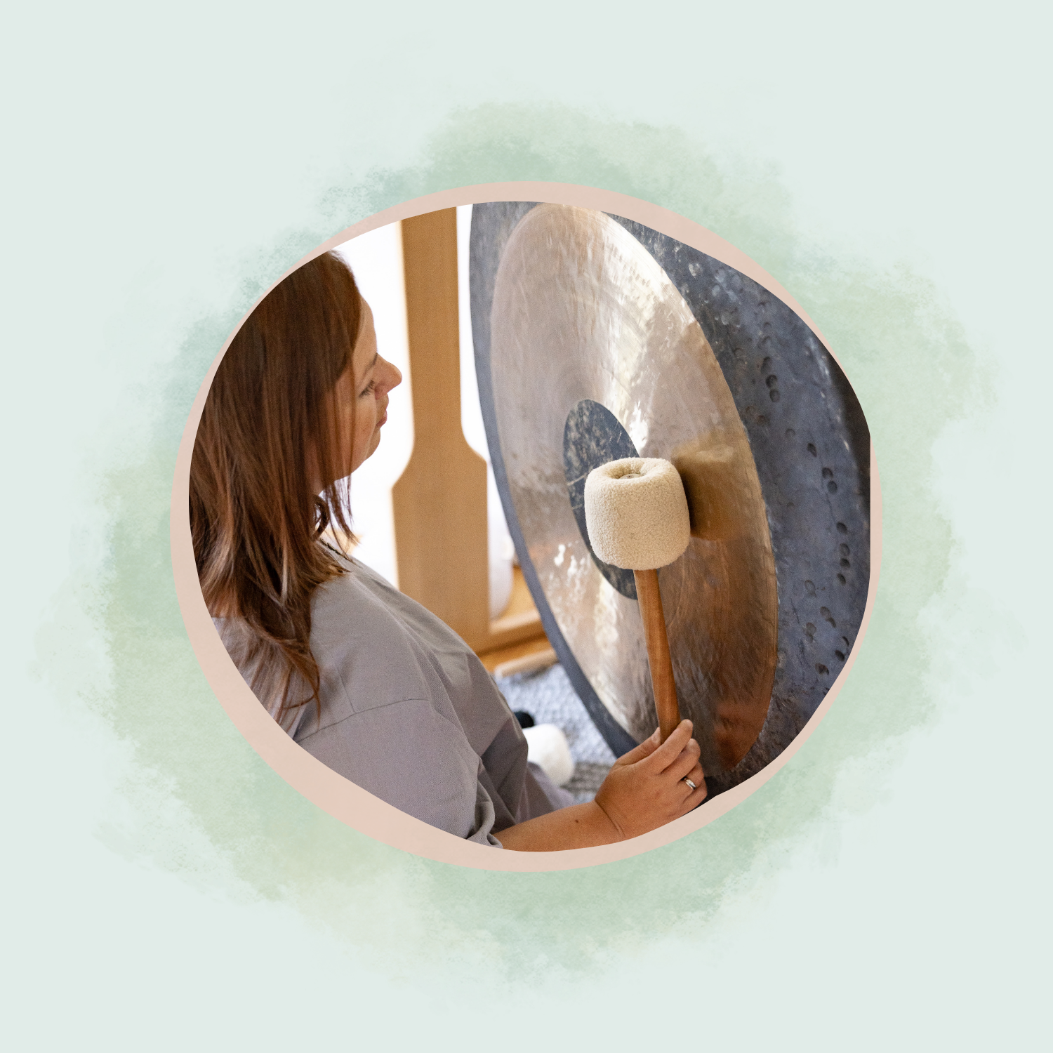 Julia Pantou sitzt nah am Gong, mit einem Gongschlegel in der rechten Hand. Bild zeigt eine Situation beim Klangbad.