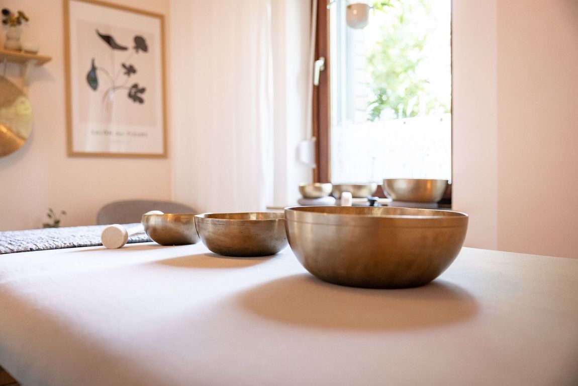 Drei verschiedene Klangschalen stehen auf der Massageliege im Klangraum des Ateliers.