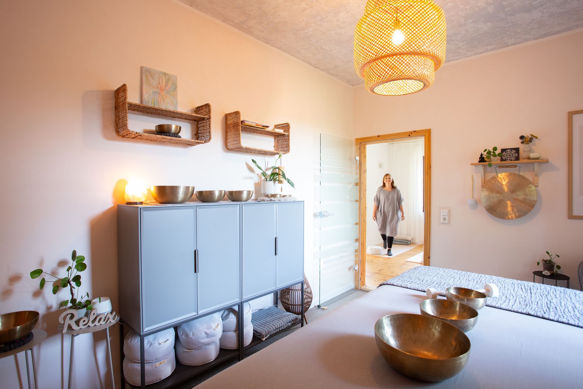 Julia Pantou betritt den Klangraum mit vielen Klangschalen, sie geht durch den Türrahmen hinein.