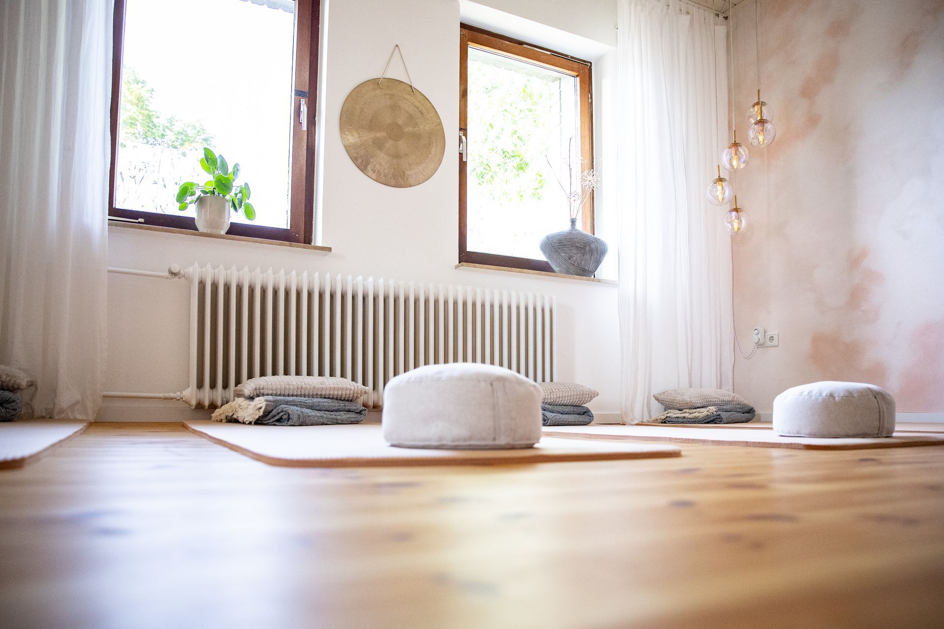 Entspannungsraum, Yogamatten und Kissen auf dem Boden, ein Gong hängt an der Wand, zwischen zwei Fenstern