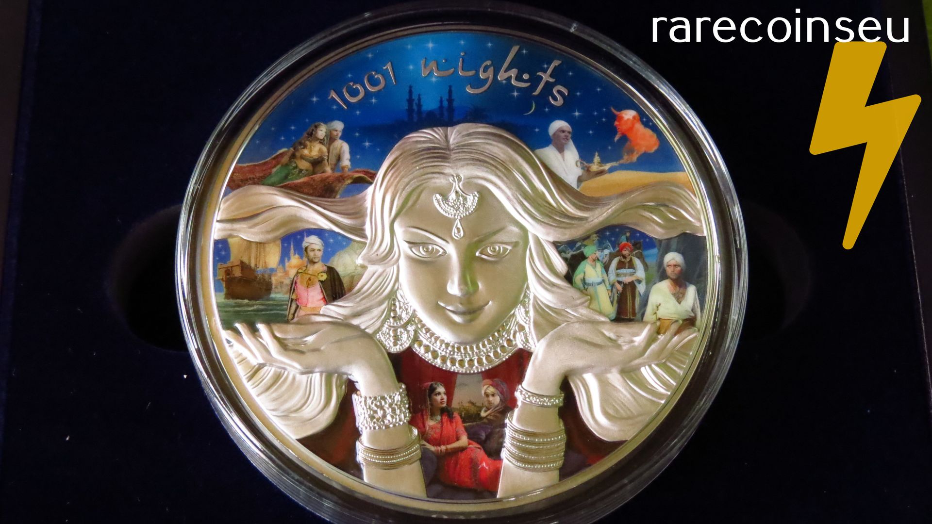 Silver commemorative coin with a face in the center, blue sky background, and two figures below the portrait