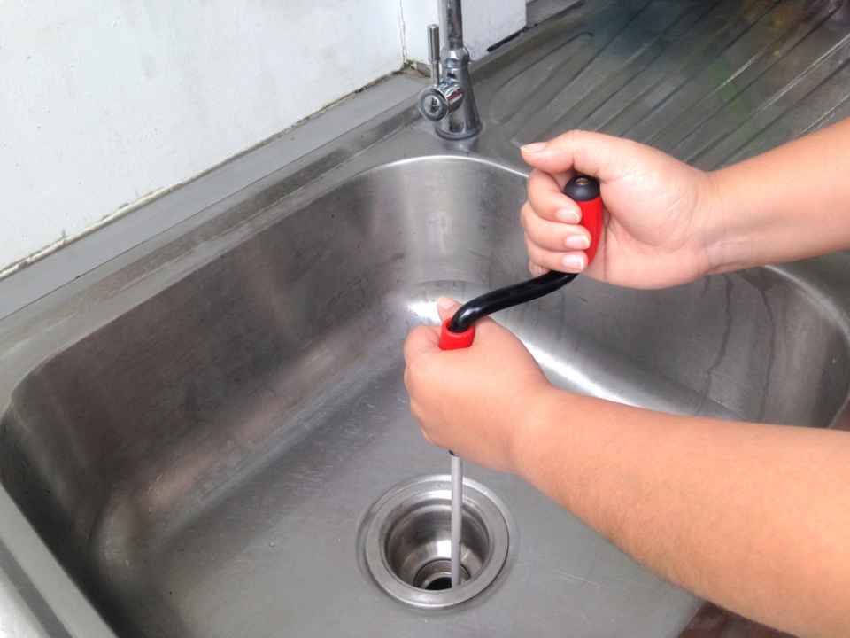 a man clearing a kitchen sink drain