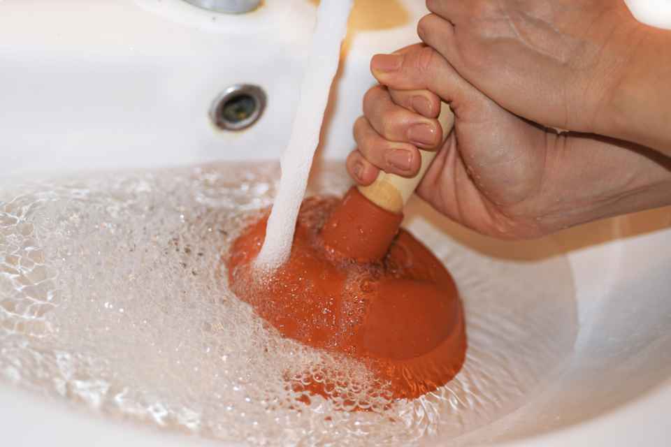 a person plunging a sink drain