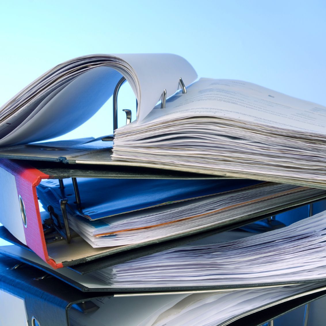 Stapel offener Ringordner voller Papiere.