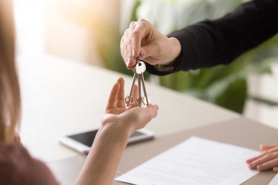 a person handing a set of keys over to a smiling couple