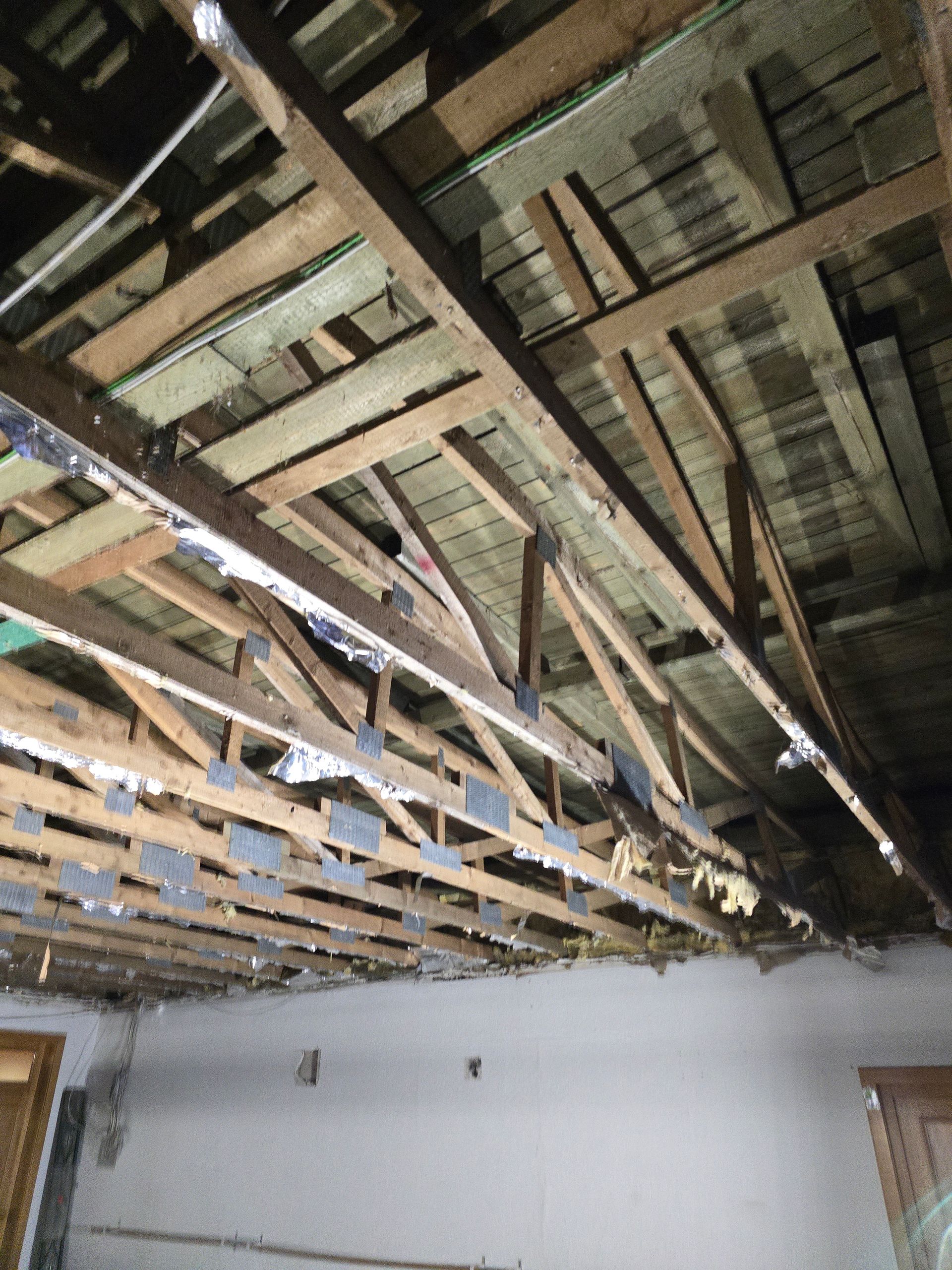 Holzdachkonstruktion mit sichtbaren Balken und Fachwerkträgern.