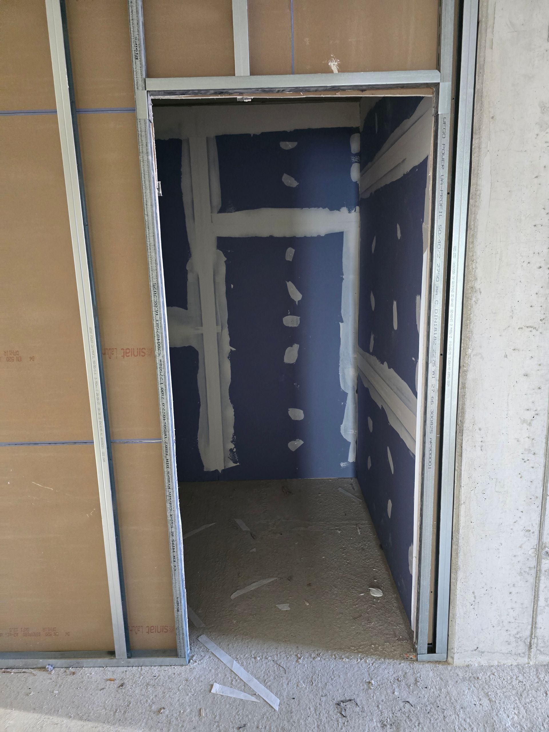 Innentür im Bau: Metallständer, Gipskartonwände und unfertiger Fußboden.