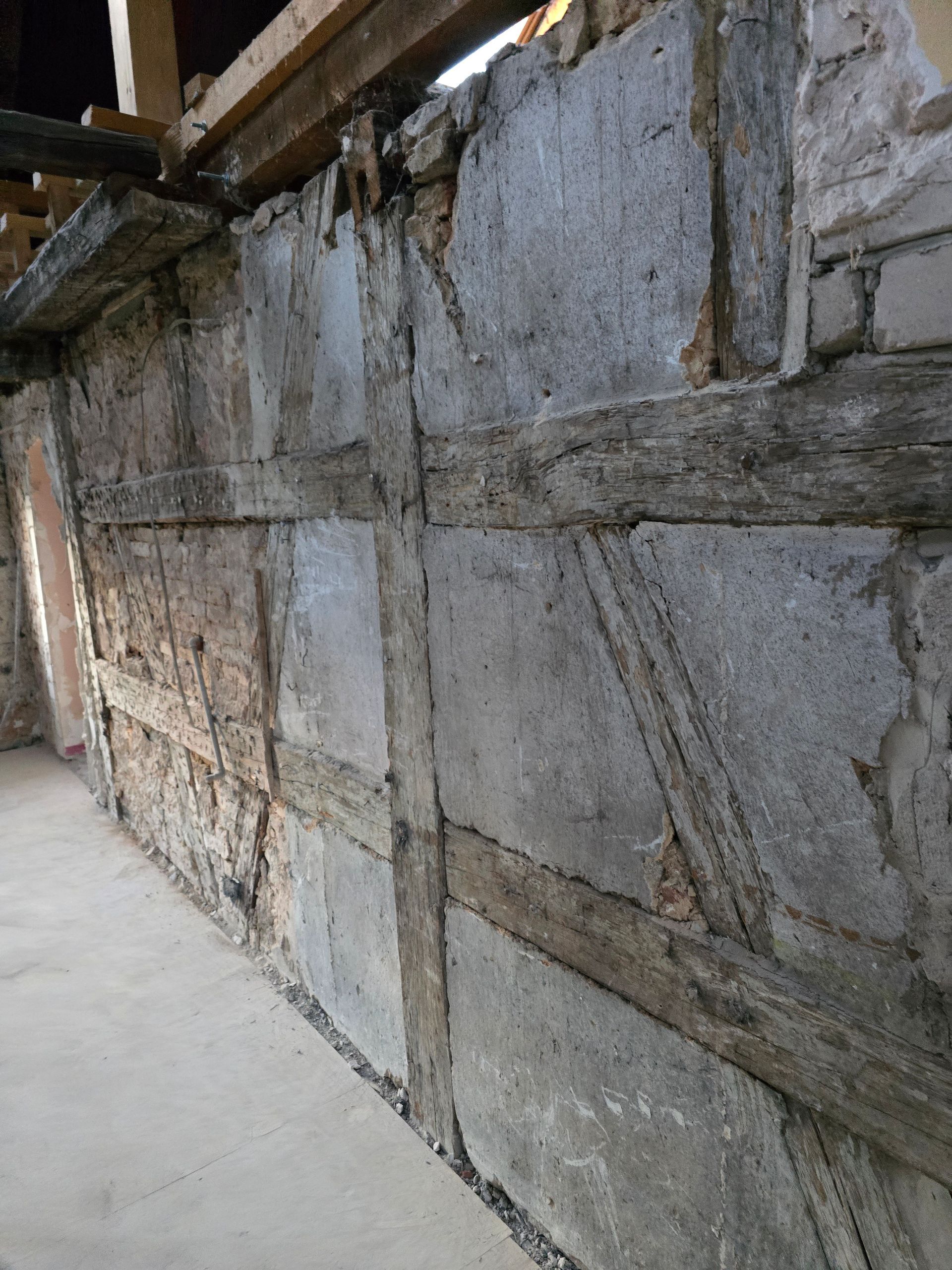 Wand mit freiliegenden Holzbalken und grauer Steinfüllung.