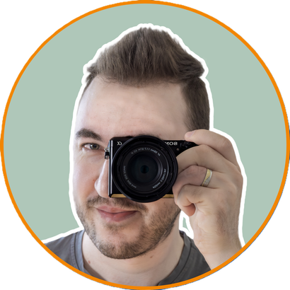 Porträt von Fotograf Jonathan aus Lohmar, mit Sony Kamera, Viltrox Objektiv und freundlichem Blick vor hellem Hintergrund.
