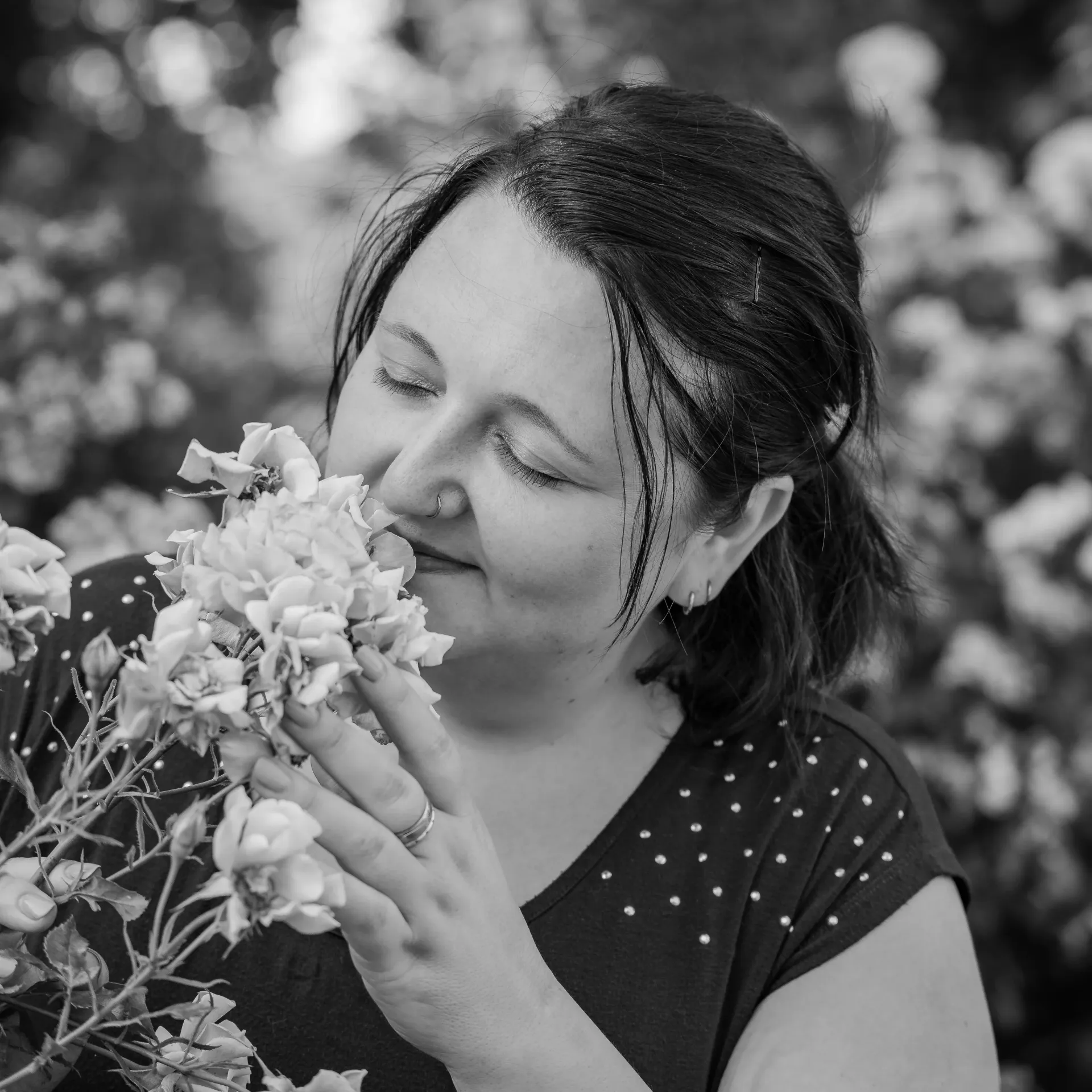 Frau mit geschlossenen Augen, riecht im Rosengarten der Abtei Michaelsberg an einer Rose, schwarz-weiß.