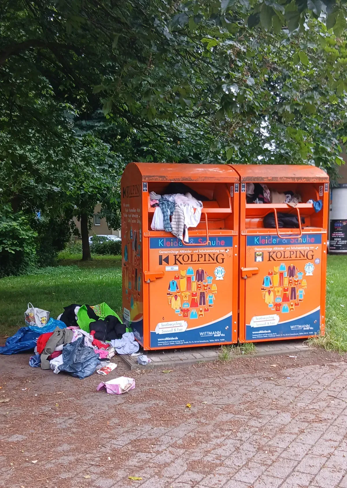 Überfüllte Altkleidercontainer mit Kleidung davor in Duisburg-Hamborn