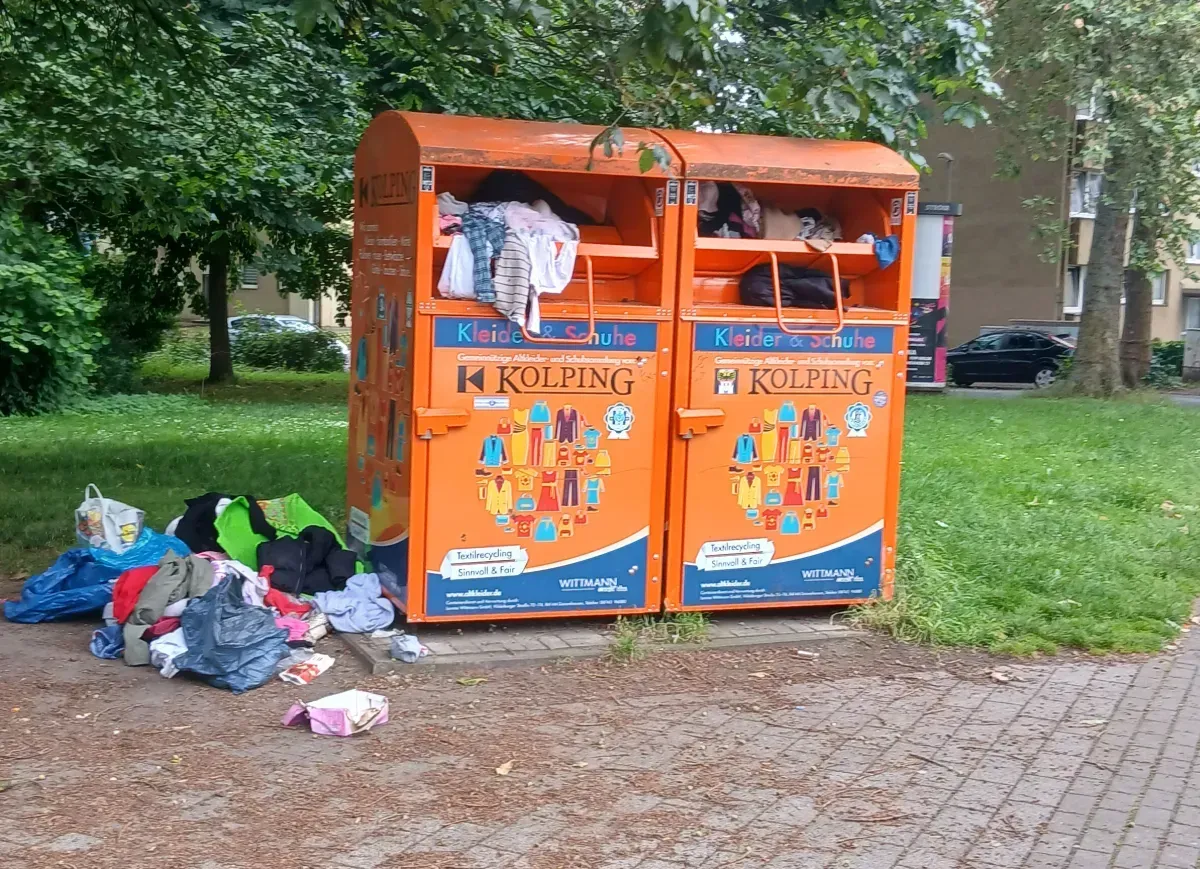 Kleidung und Säcke vor überfüllten Altkleidercontainern in Duisburg-Hamborn