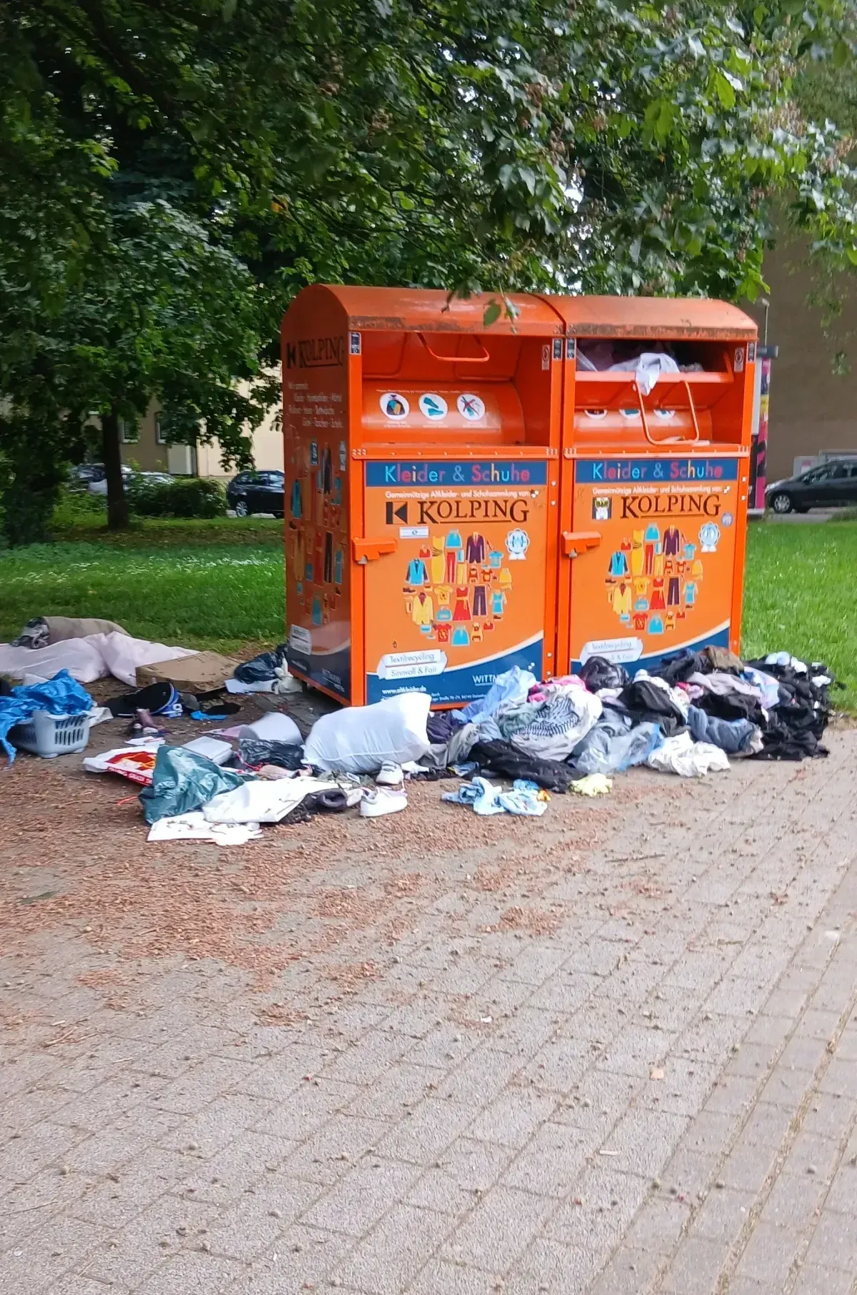 Altkleidercontainer in Duisburg-Hamborn mit vielen Kleidungsstücken und Abfällen davor einfach abgestelt