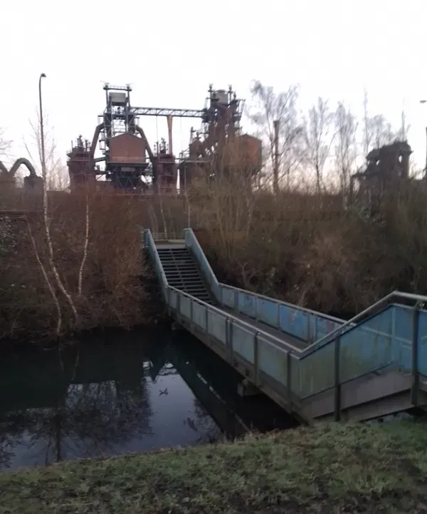  Brücke am Wasser mit Industrieanlage im Landschaftspark
