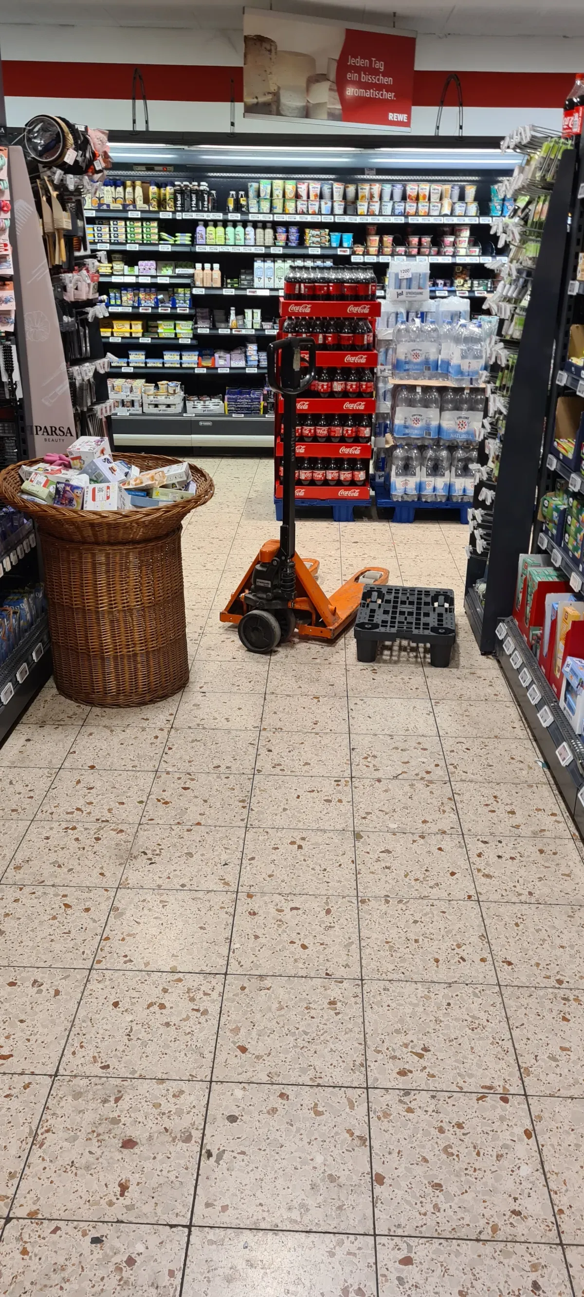 Hubwagen und Verkaufskorb im Einkaufsgang eines Rewe-Marktes
