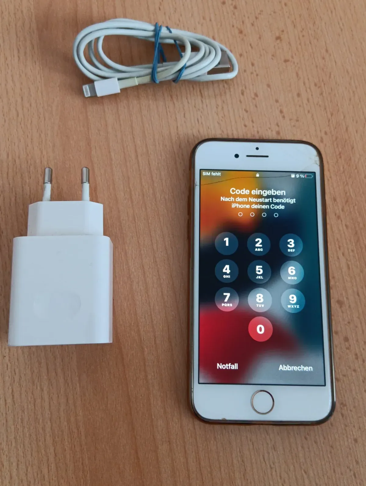 Smartphone IPhone 8 Weiß mit Stromkabel und USB Kabel. Handy ist eingeschaltet.