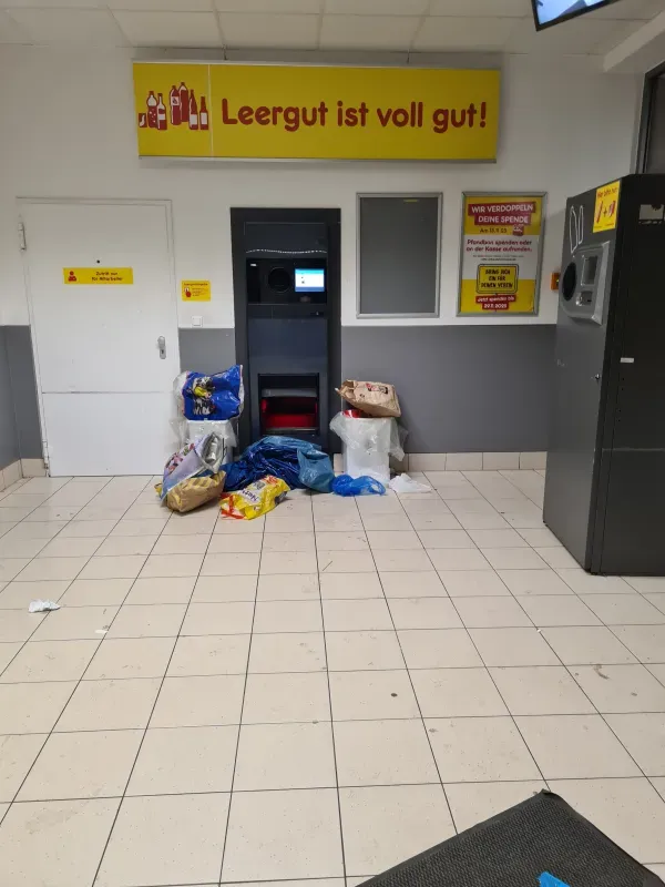 Leergutautomaten mit abgestellten Pfandflaschen und Beuteln auf dem Boden.2