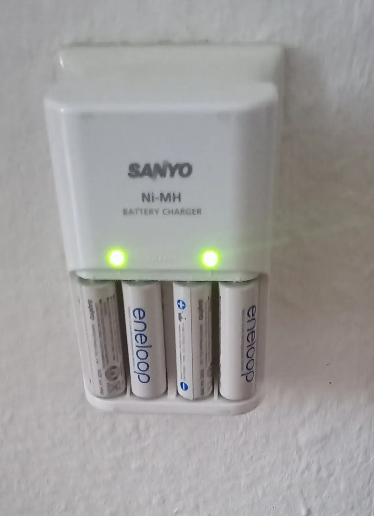 Weißes Akku Ladegerät Sanyo Ni-MH  mit 4 Batterien drin steckt in der Stromdose zu aufladen Gebraucht.