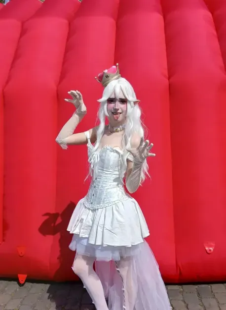 Cosplayerin mit weißem Kostüm und Krone vor einer roten Hüpfburg beim Japan-Tag Düsseldorf 2026