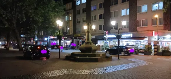 Beleuchteter Steinbrunnen auf dem Hamborner Marktplatz in Duisburg bei Nacht.