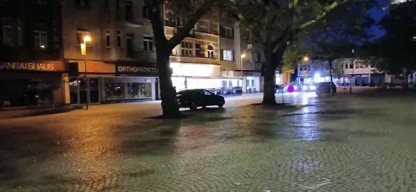 Hamborner Marktplatz mit Bäumen und beleuchteten Geschäften bei Nacht.