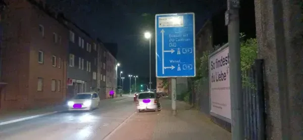 Beleuchtetes Hinweisschild Richtung Duisburg-Zentrum und Wesel bei Nacht.