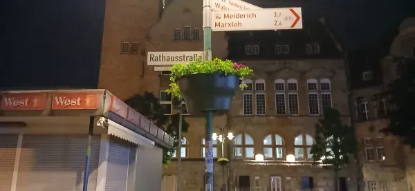 Rathaus Hamborn und Rathausstraße mit Kiosk und Straßenschild bei Nacht