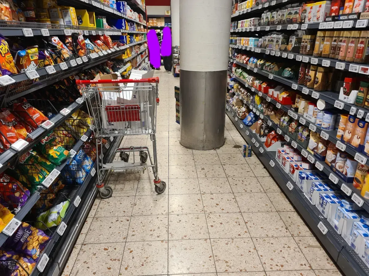 REWE Duisburg‑Hamborn mit leerem Einkaufswagen und Ware am Boden.