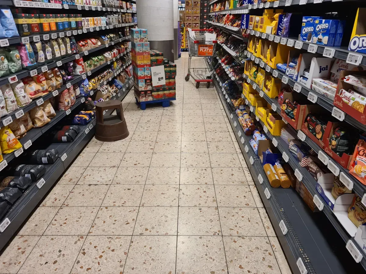 REWE Duisburg‑Hamborn mit Einkaufswagen, leeren Kartons und Ware auf Paletten.